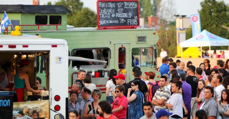 crowd of people gathered around food trucks