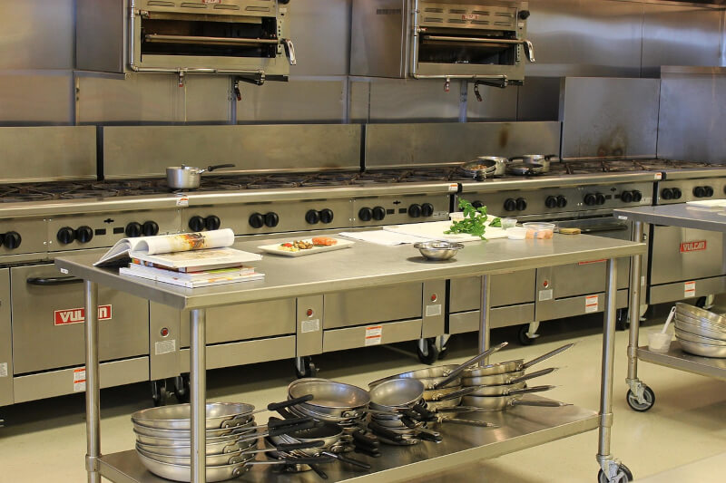 commercial commissary kitchen with a large burner stove, pots and pans, and food on the prep table
